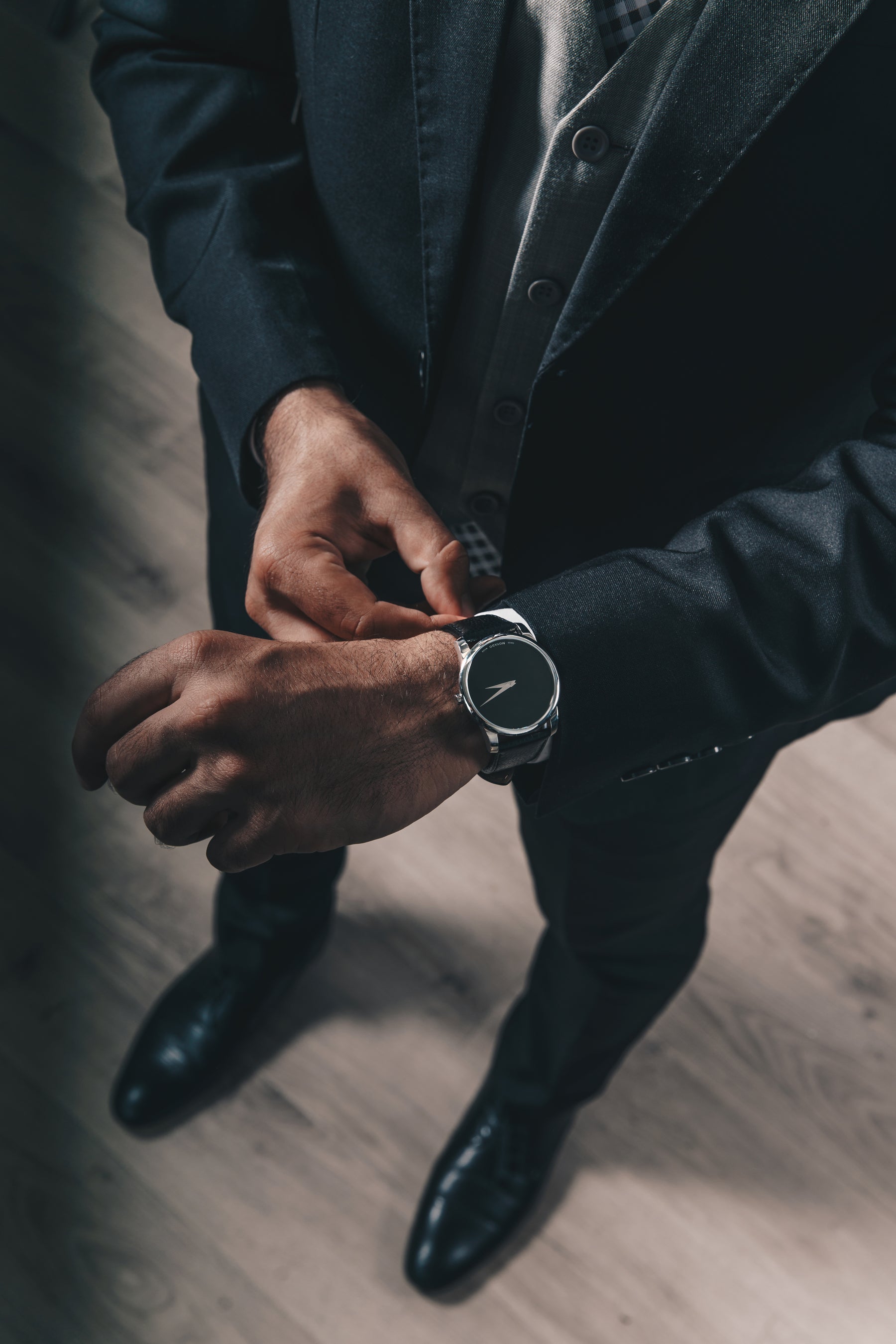 bearded man in suit adjusting his watch
